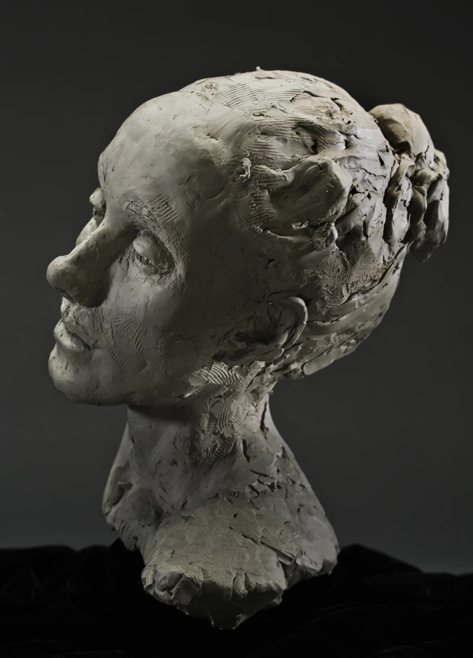 A sculpted head seen in profile against a dark ground.
